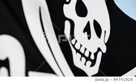 Black pirate flag with skull symbol on the desert island Black pirate flag with skull symbol on the desert island 94741928