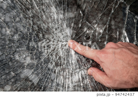 Male hand points broken window glass 94742437