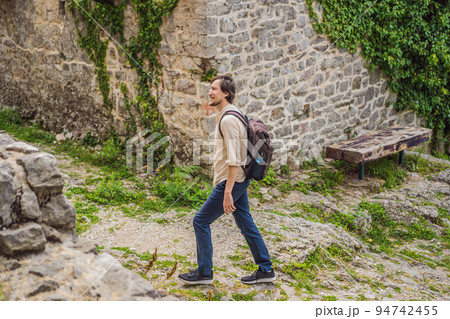 Man tourist walks through the old town of Bar in Montenegro. Happy tourist walks in the mountains. Suburbs of the city of Bar, Montenegro, Balkans. Beautiful nature and landscape 94742455