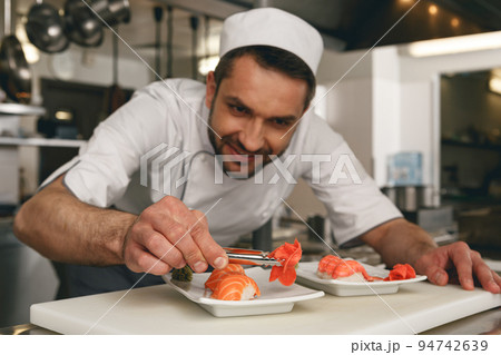 Sushi master prepares sushi for serving in modern commercial kitchen Sushi master prepares sushi for serving in modern commercial kitchen 94742639