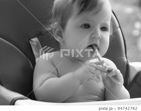 Happy baby sitting in high chair eating puree 94742762