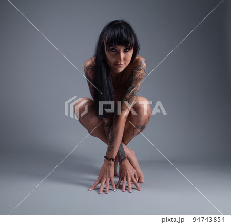 Photo of the nude girl with tattoo sitting on the floor 94743854