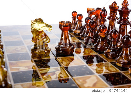 Natural amber different chess pieces figures standing on brown stone board. Close up game concept competition, Classic Gambit Tournament of confrontation. 94744144