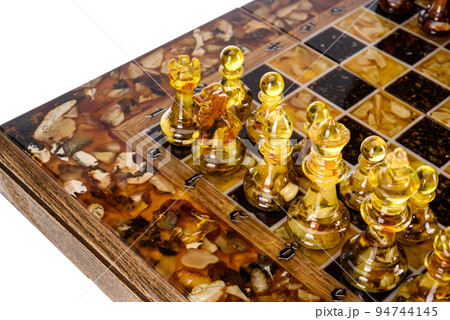 Natural amber different chess pieces figures standing on brown stone board. Close up game concept competition, Classic Gambit Tournament of confrontation. 94744145