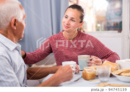 Mature man with daughter talking at table with cup of tea 94745139