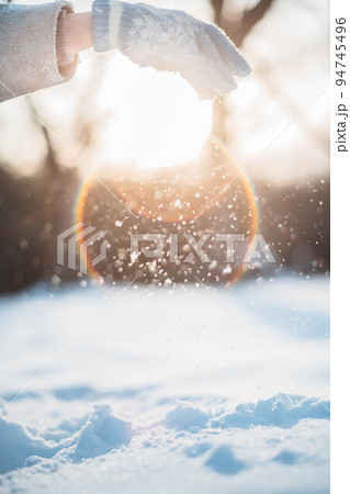 逆光の中、雪を掴む女性 94745496