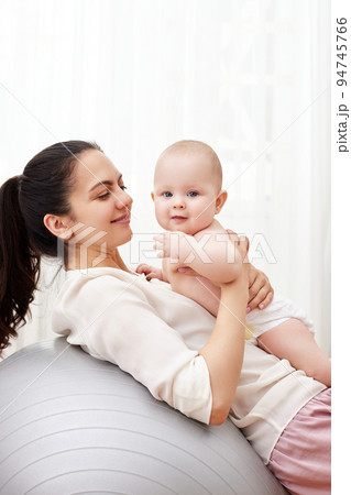 mother playing with her baby girl on a fitness ball mother playing with her baby girl on a fitness ball 94745766