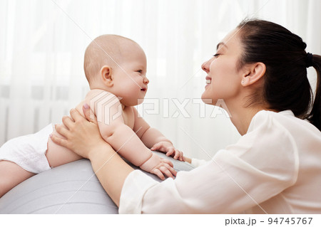 mother playing with her baby girl on a fitness ball 94745767