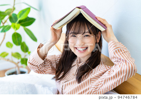 ベッドで本を読む眼鏡の若い女性 ベッドで本を読む眼鏡の若い女性 94746784