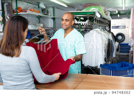 Man dry-cleaning worker giving clothes to customer Man dry-cleaning worker giving clothes to customer 94748302