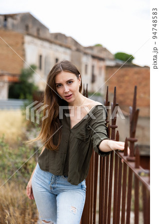 Street style photo of fashionable woman wearing trendy clothes. Model walking in street near wrought-iron fence Street style photo of fashionable woman wearing trendy clothes. Model walking in street near wrought-iron fence 94748583