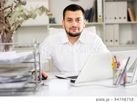 Positive man office worker using laptop during workday 94748758
