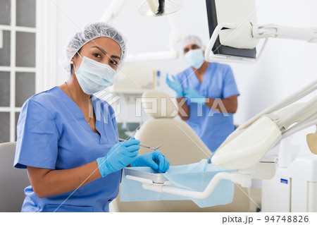 Nurse prepares instruments before the patient is seen by dentist 94748826