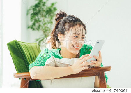 ソファに寝転がってスマホを見る女性 ソファに寝転がってスマホを見る女性 94749061