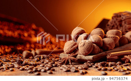 Chocolate truffles with cinnamon, anise, and coffee beans on a wooden table. Chocolate truffles with cinnamon, anise, and coffee beans on a wooden table. 94756374
