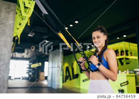 Woman doing exercises with trx fitness straps in the gym Woman doing exercises with trx fitness straps in the gym 94756459