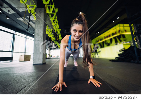 Woman in blue top and leggings practicing yoga performing 94756537