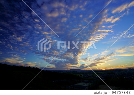 秋の夕焼け・広がるうろこ雲と飛行機雲・日没後の写真素材 [94757348