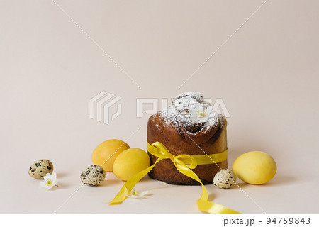 Easter composition of sweet bread cake, white flowers and yellow and quail eggs on a light background. Orthodox Easter bread. A festive breakfast concept with space for text. Easter composition of sweet bread cake, white flowers and yellow and quail eggs on a light background. Orthodox Easter bread. A festive breakfast concept with space for text. 94759843