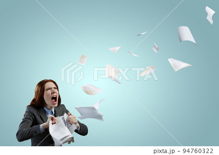 Young stressed woman ripping documents with frustrated facial expression. 94760322
