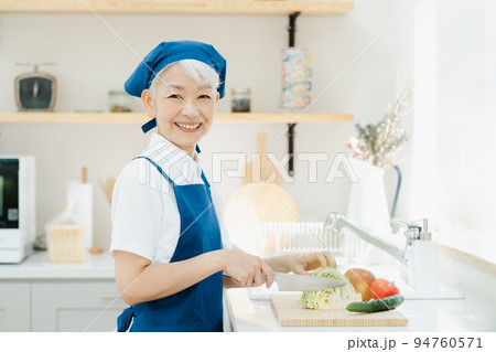 キッチンで料理をするハウスキーパーのシニア女性 キッチンで料理をするハウスキーパーのシニア女性 94760571