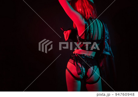woman with a sexy ass with red hair in beautiful underwear holds leather whip flogger in her hand for BDSM sex 94760948