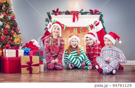 Group of children sitting on the floor indoors on Christmas morning. Group of children sitting on the floor indoors on Christmas morning. 94761129