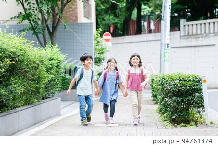 手を繋いで歩道を歩く小学生 94761874