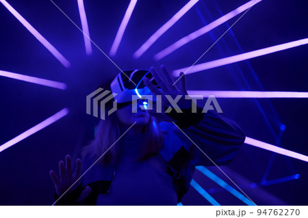 Woman is using virtual reality headset to access in metaverse. 94762270