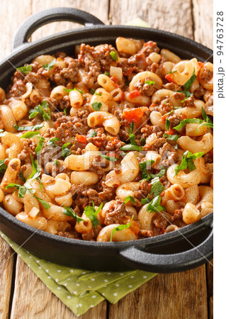 Comfort food ground beef cooked with onions, tomato sauce, and macaroni closeup in the pan on the wooden table. Vertical 94763728