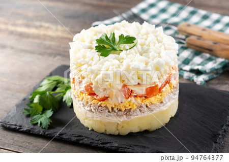 Traditional Russian layered salad Mimosa on wooden table Traditional Russian layered salad Mimosa on wooden table 94764377