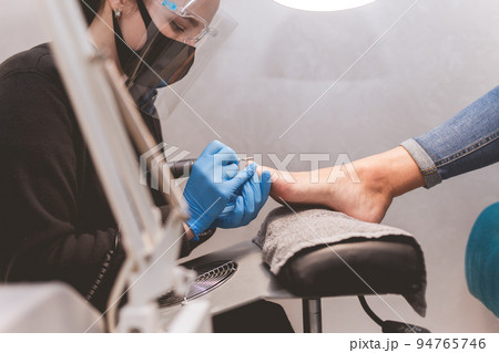 Pedicure master polishes nails with nail file drill before applying varnish side view. Pedicure master polishes nails with nail file drill before applying varnish side view. 94765746