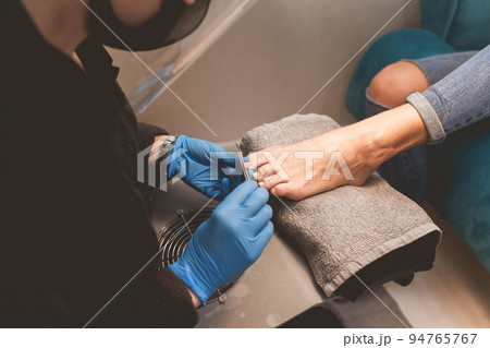Pedicure master files nails with a nail file for subsequent application of varnish. Pedicure master files nails with a nail file for subsequent application of varnish. 94765767
