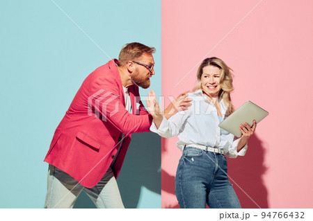 Expressive young people, man and woman, husband and wife spending time together isolated over blue and pink background. Expressive young people, man and woman, husband and wife spending time together isolated over blue and pink background. 94766432