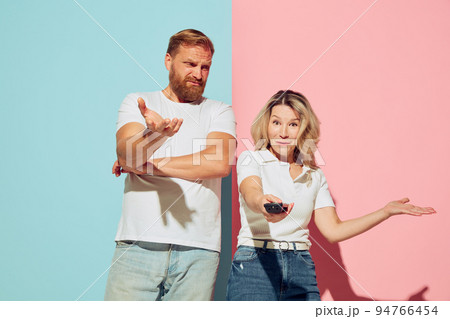 Expressive young people, man and woman, husband and wife spending time together isolated over blue and pink background. Expressive young people, man and woman, husband and wife spending time together isolated over blue and pink background. 94766454