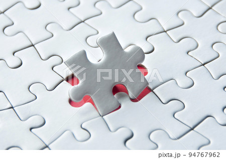 White jigsaw puzzle on red cover background with customizable space for text. Copy space and puzzle concept 94767962