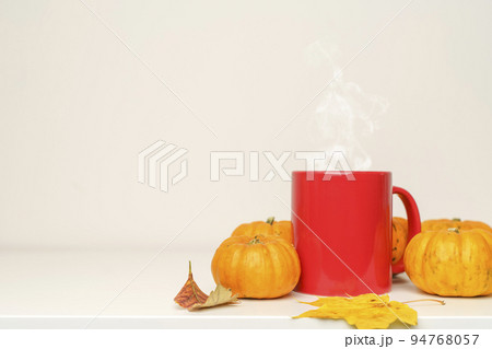 A cup of hot autumn drink coffee or tea with pumpkins and fall decor on an empty white background. A cup of hot autumn drink coffee or tea with pumpkins and fall decor on an empty white background. 94768057