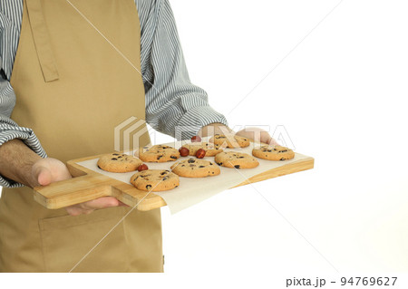 Young man holds board with cookies, isolated on white background 94769627