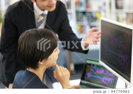 先輩からCAD操作のレクチャーを受ける女性設計者_5 94770981