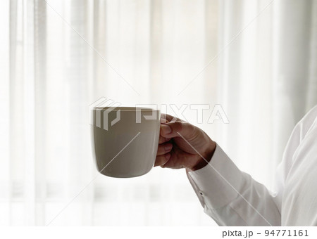 窓際でコーヒーを飲む男性の手元 窓際でコーヒーを飲む男性の手元 94771161