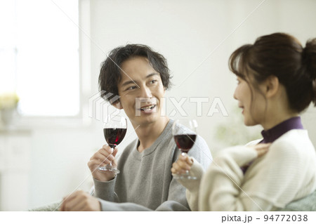 リビングでワインを飲む若いカップル 94772038