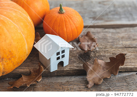 Autumnal Background. Toy house and pumpkin on wooden background. Thanksgiving banner copy space. Hygge mood, change of seasons concept. Hello Autumn with family Halloween party Autumnal Background. Toy house and pumpkin on wooden background. Thanksgiving banner copy space. Hygge mood, change of seasons concept. Hello Autumn with family Halloween party 94772772