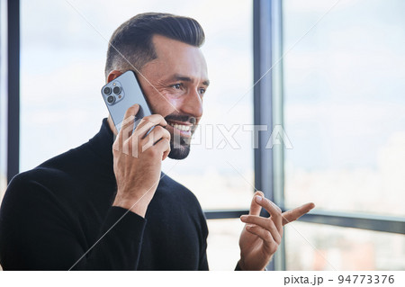 businessman with a smartphone standing near the window. 94773376