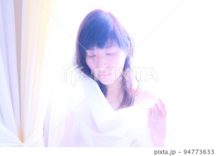 朝陽を浴びながらカーテンを持つ女性の姿 朝陽を浴びながらカーテンを持つ女性の姿 94773633