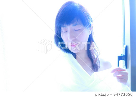 朝陽を浴びながらカーテンを持つ女性の姿 朝陽を浴びながらカーテンを持つ女性の姿 94773656