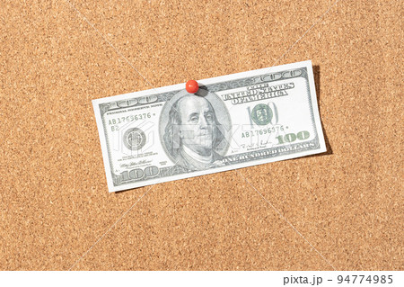 Fake one hundred dollar banknote pinned on cork board 94774985
