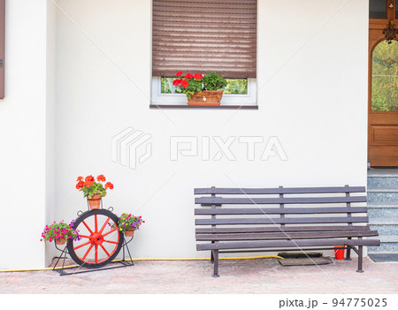Traditional Alps front door. Wooden bench, flowers and some decoration. Traditional Alps front door. Wooden bench, flowers and some decoration. 94775025