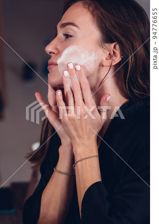 Young woman washing her face with cleansing foam 94776655