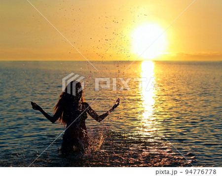 girl standing in the lake water in the rays of the setting sun girl standing in the lake water in the rays of the setting sun 94776778