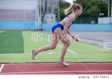 Young caucasian woman is engaged in jogging at the stadium outdoors. Young caucasian woman is engaged in jogging at the stadium outdoors. 94778851